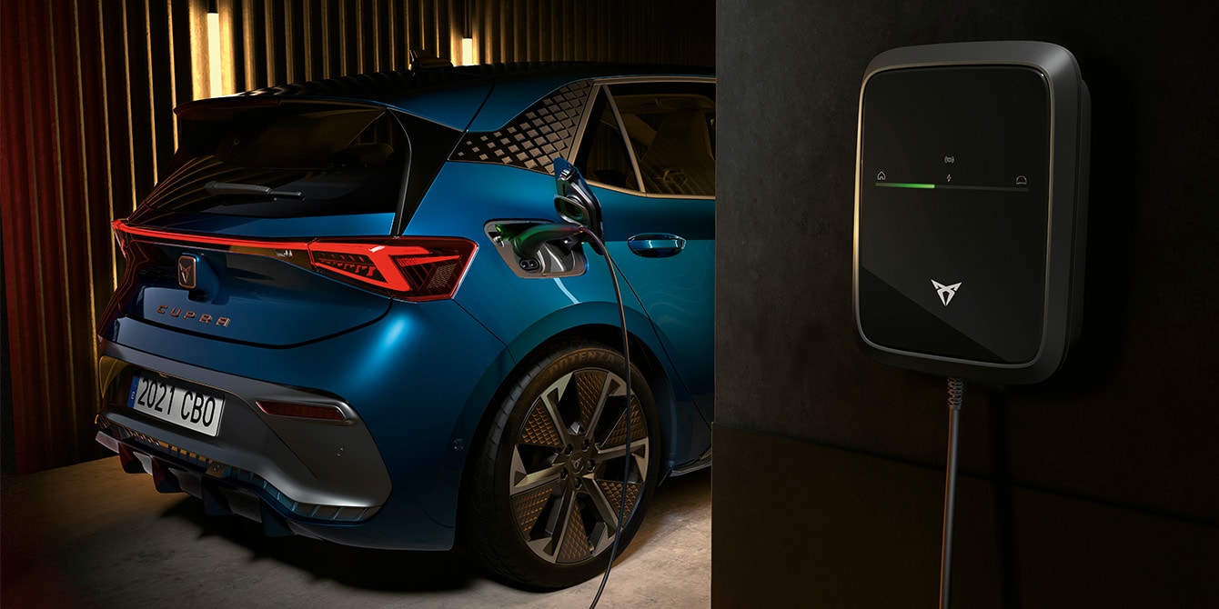 CUPRA Born 100% eléctrico cargándose en un punto de carga en la azotea de un edificio con vistas a la ciudad.