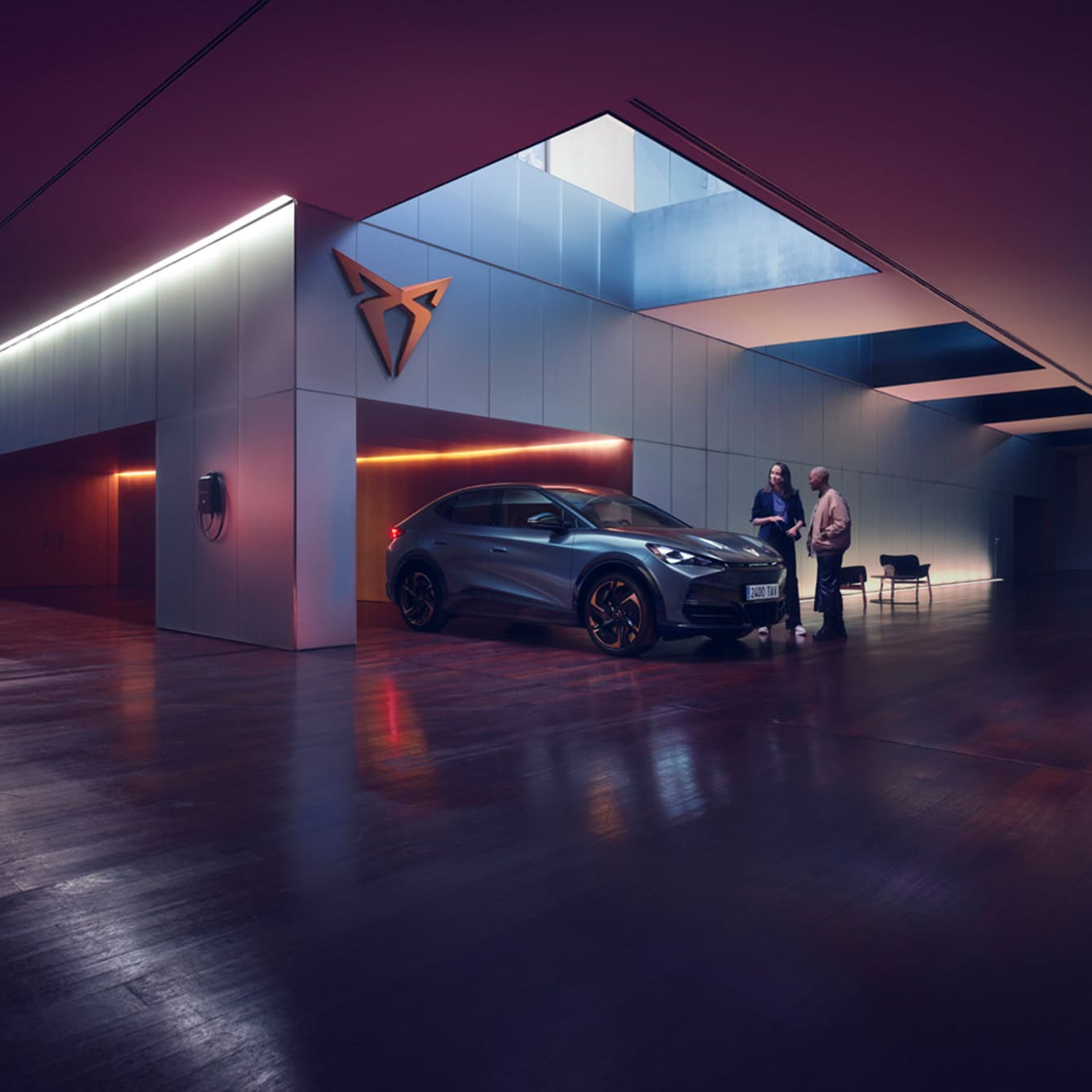 CUPRA Tavascan en un espacio de exposición moderno con iluminación ambiental púrpura.