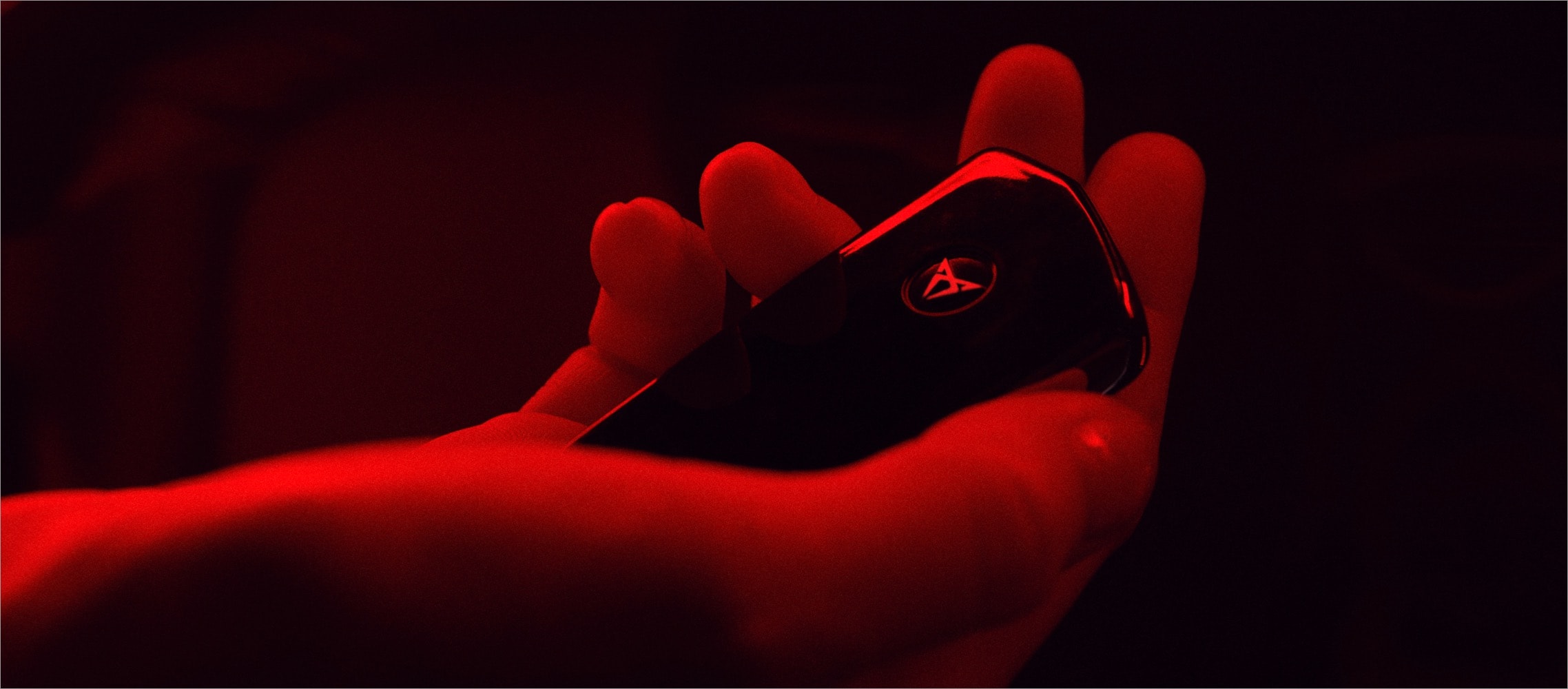Mano sosteniendo la llave de un coche CUPRA con ambiente iluminado en color rojo