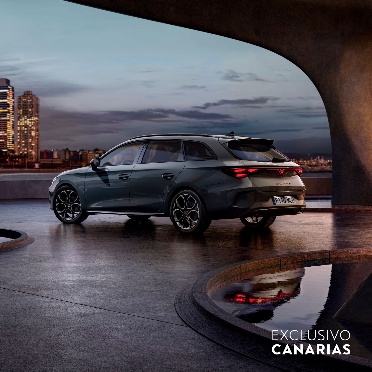 CUPRA León Sportstourer en color gris magnético aparcado en un entorno urbano nocturno con vistas a la ciudad iluminada, destacando su diseño deportivo y capacidad de maletero.