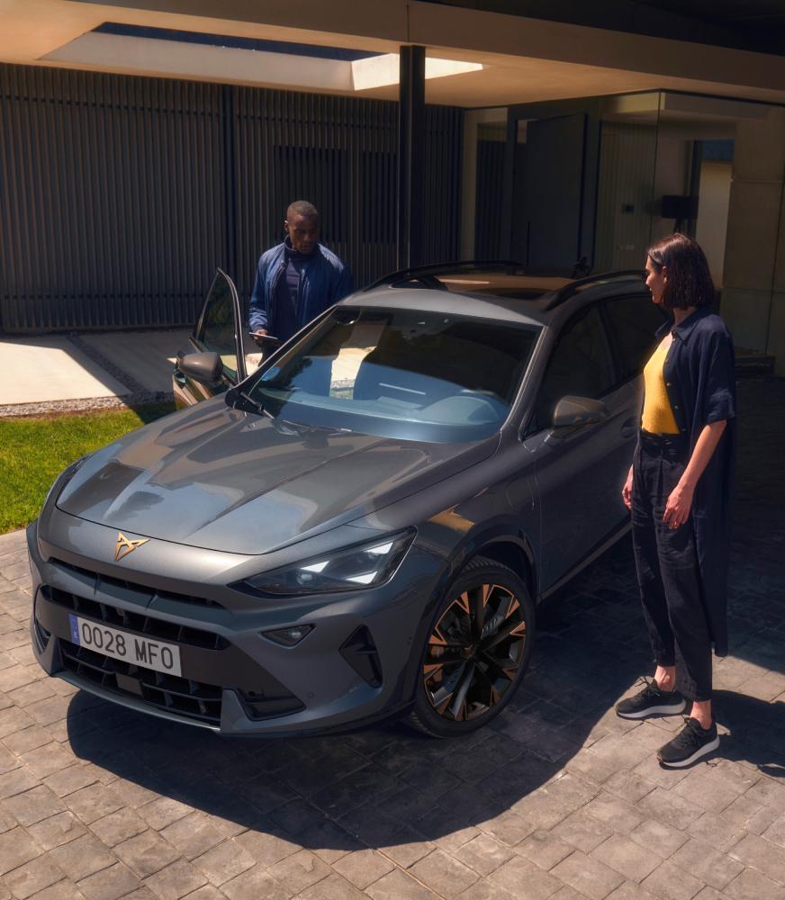 Personas%20junto%20a%20CUPRA%20Formentor%20crossover%20híbrido%20aparcado%20frente%20a%20garaje