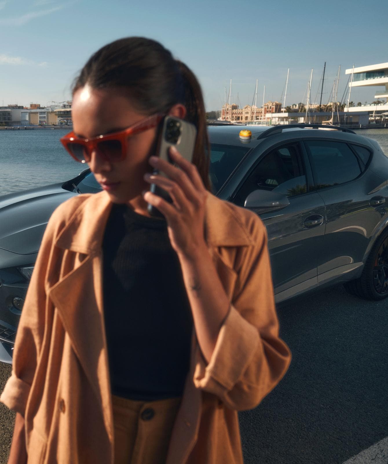 Mujer habla por teléfono frente a CUPRA Formentor crossover híbrido con una Baliza V16 instalada en el techo