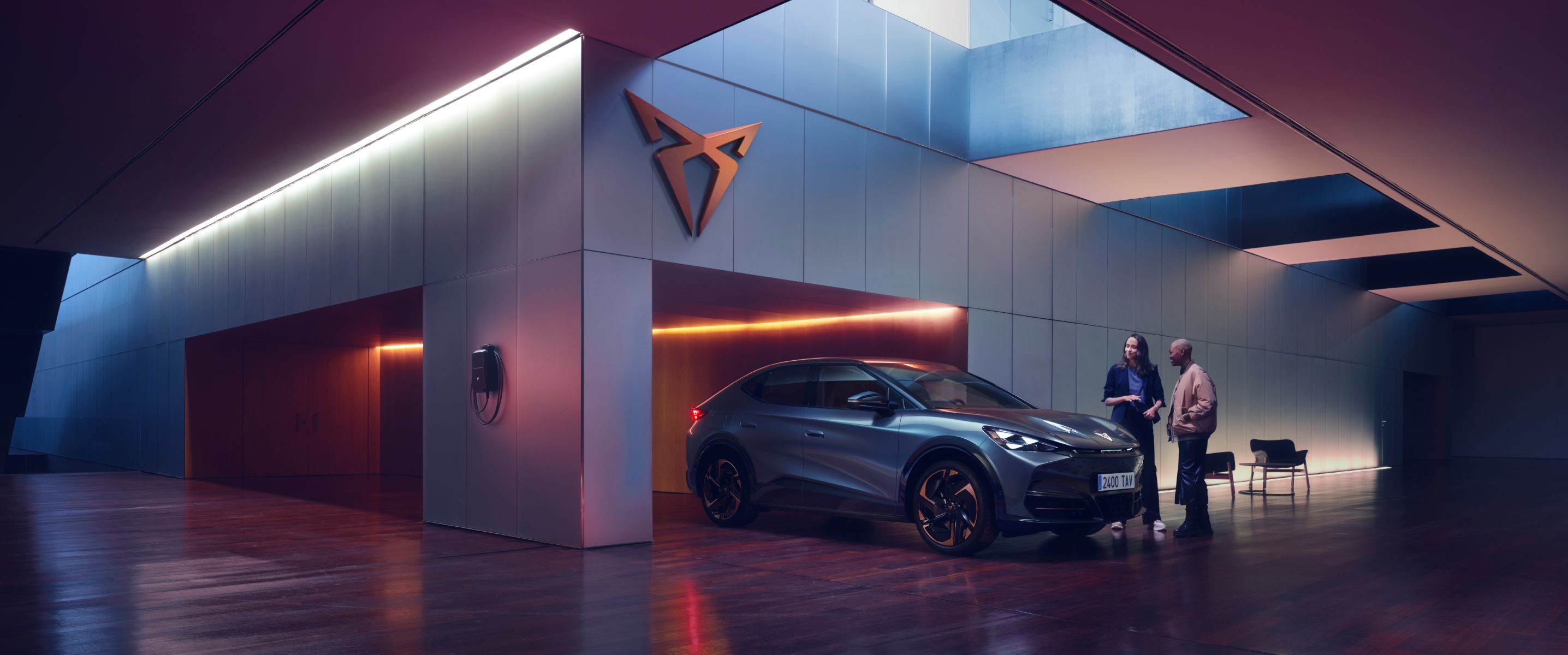 CUPRA Tavascan eléctrico en espacio de exposición moderno con iluminación ambiental púrpura.