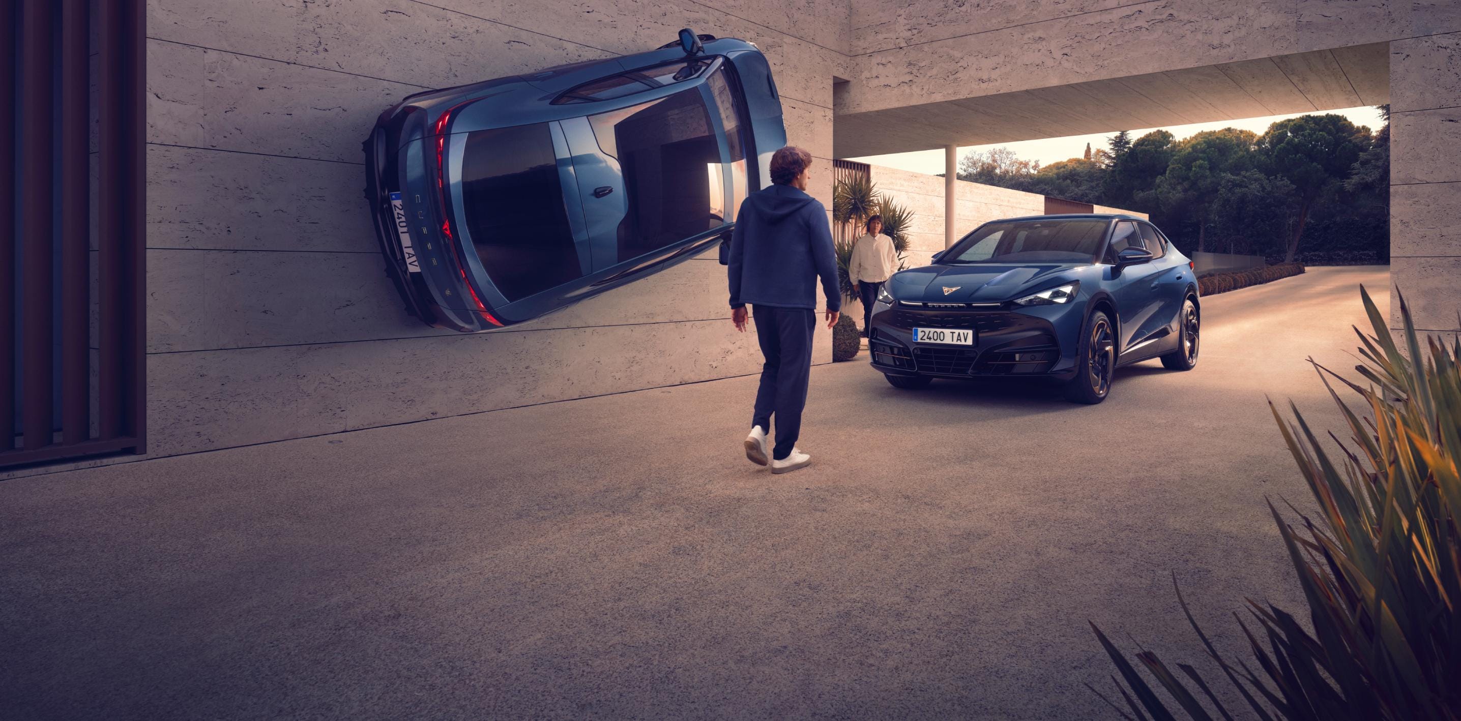 Hombres caminan cerca de dos CUPRA Tavascan 100% eléctricos frente al acceso de una vivienda.