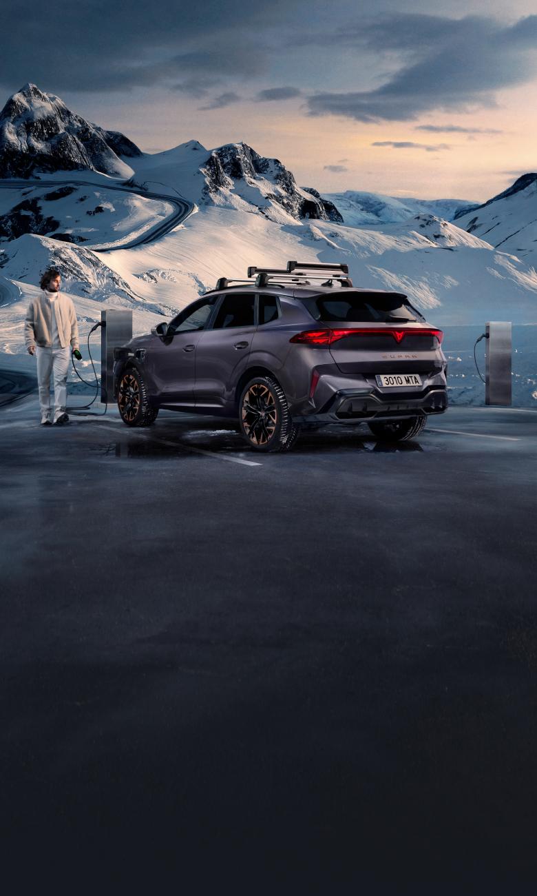 CUPRA Terramar híbrido enchufable conectado a punto de carga pública en carretera de montaña nevada