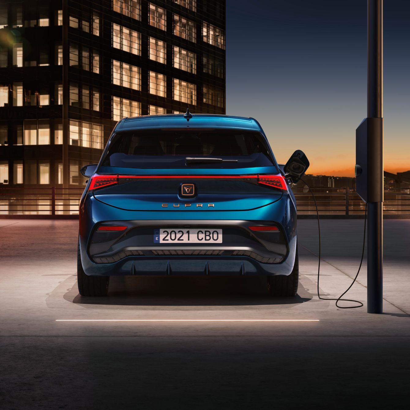 Vista trasera de un CUPRA Born 100% eléctrico conectado a estación de carga pública.