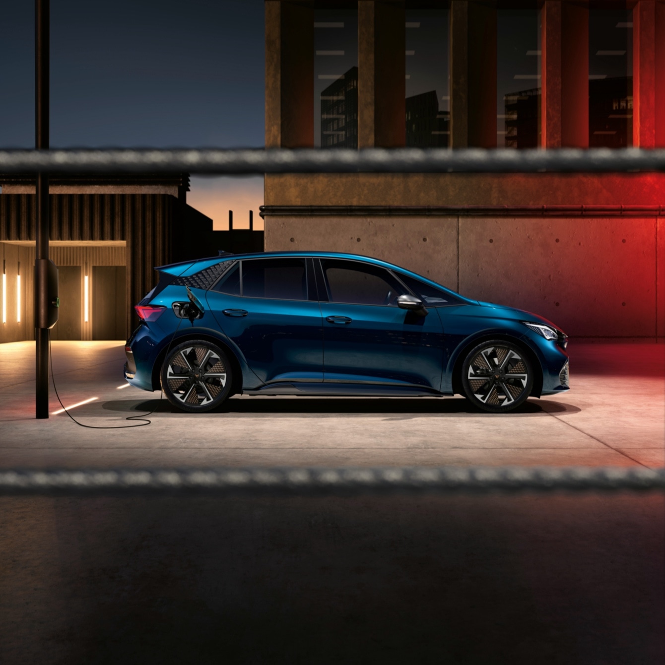 CUPRA Born 100% eléctrico color azul lava conectado a poste de carga pública
