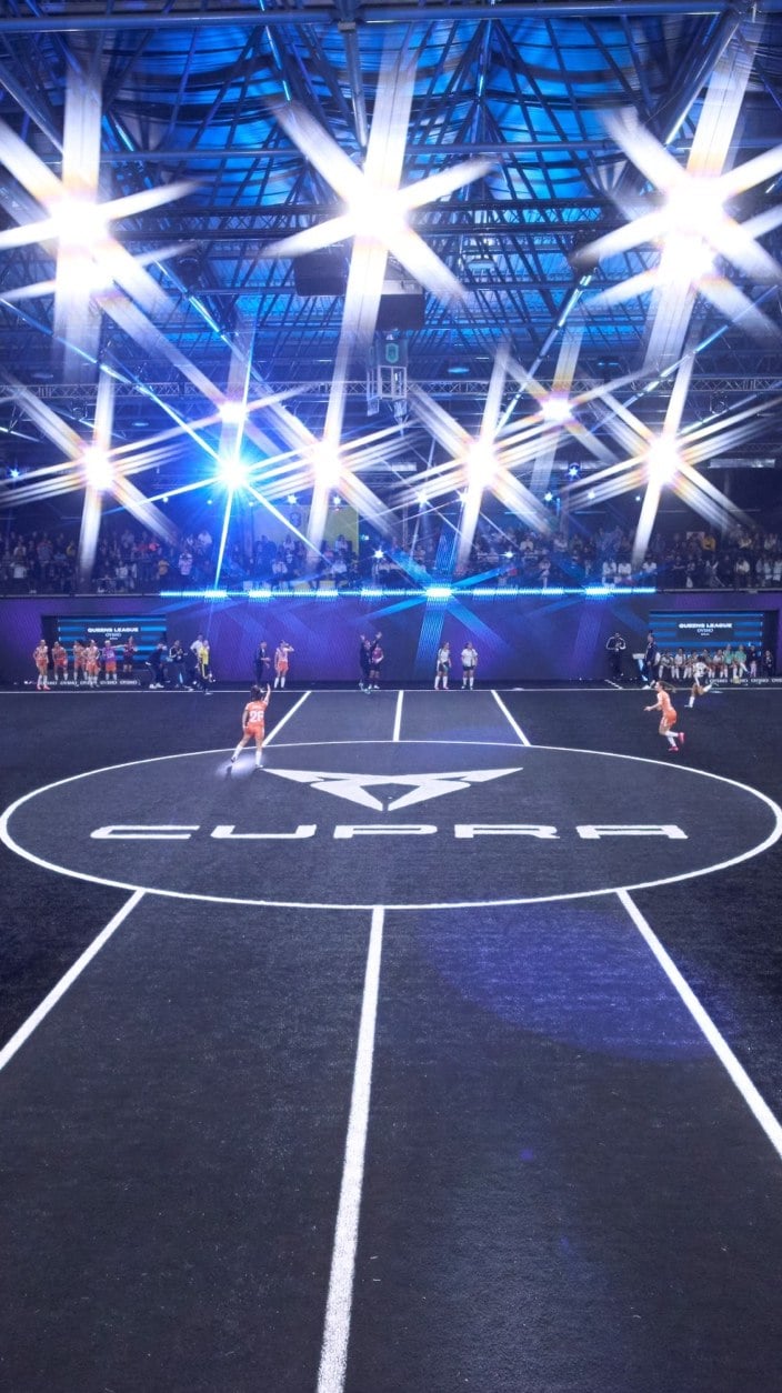Fotografía desde la banda del CUPRA Arena de Kings y Queens League con iluminación ambiente de color azul y potentes focos blancos en el techo