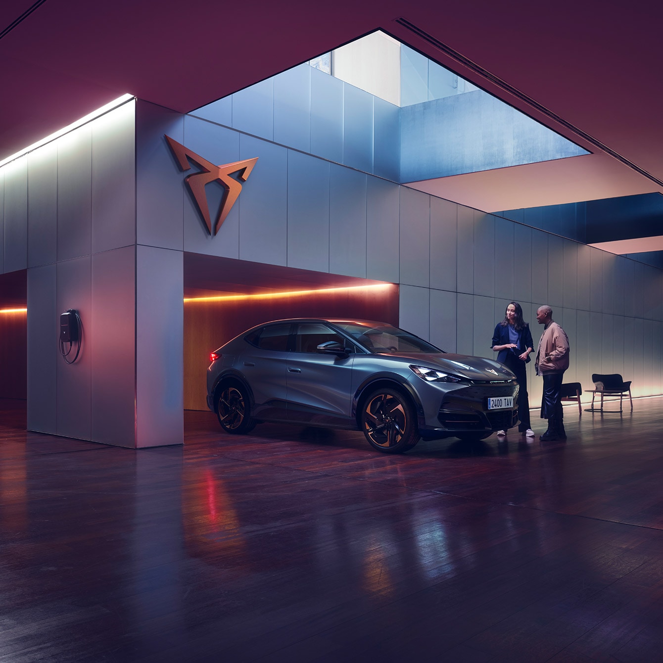CUPRA Tavascan expuesto en un moderno espacio con iluminación ambiental púrpura.