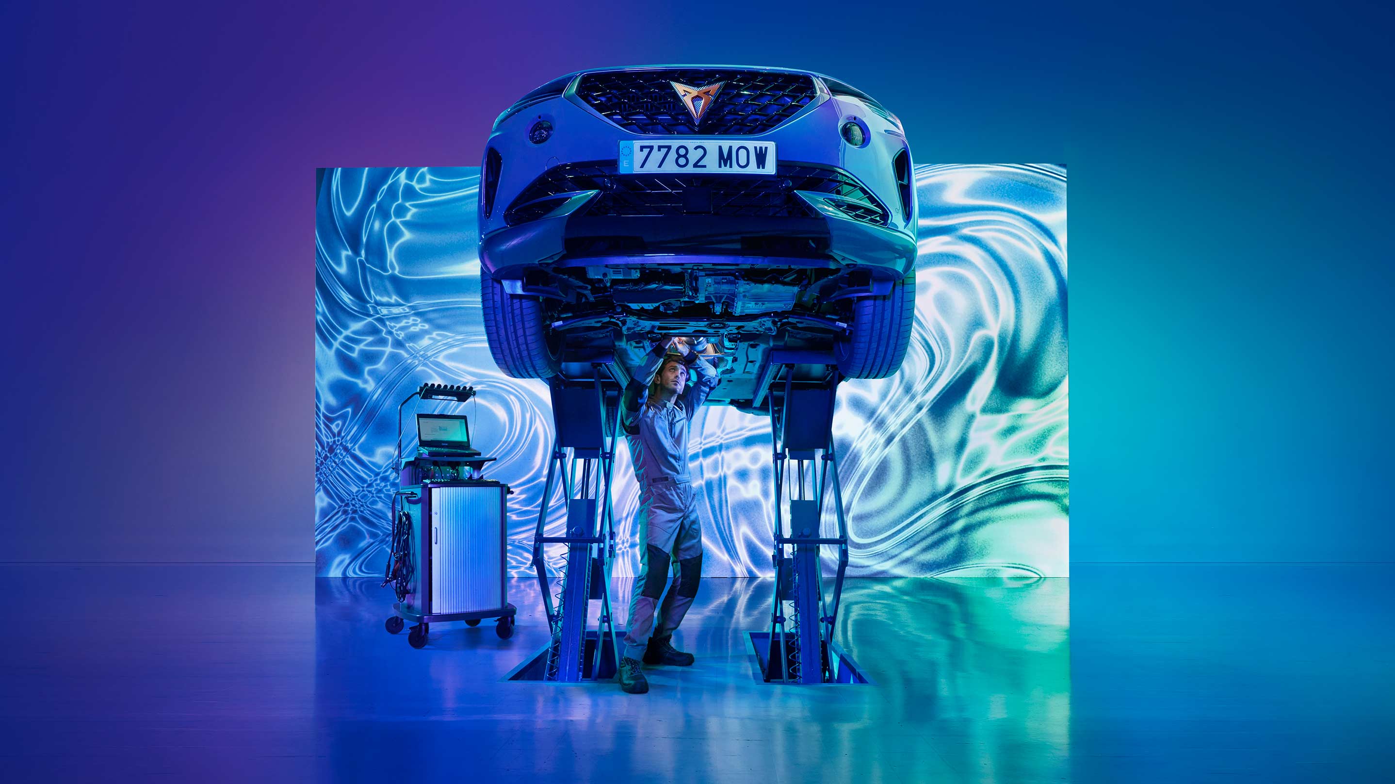CUPRA Formentor en elevador siendo inspeccionado por un especialista en taller con luces de neón azules y moradas