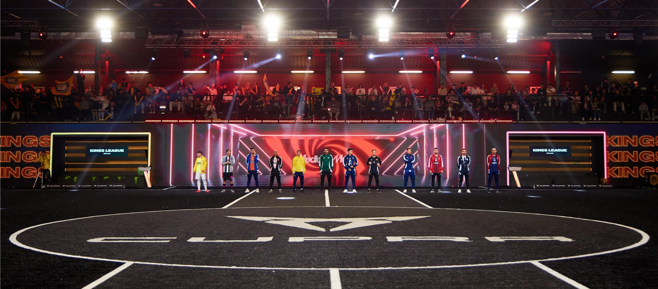 Integrantes de la Kings League posan en la banda del CUPRA Arena iluminados con luces de color rojo