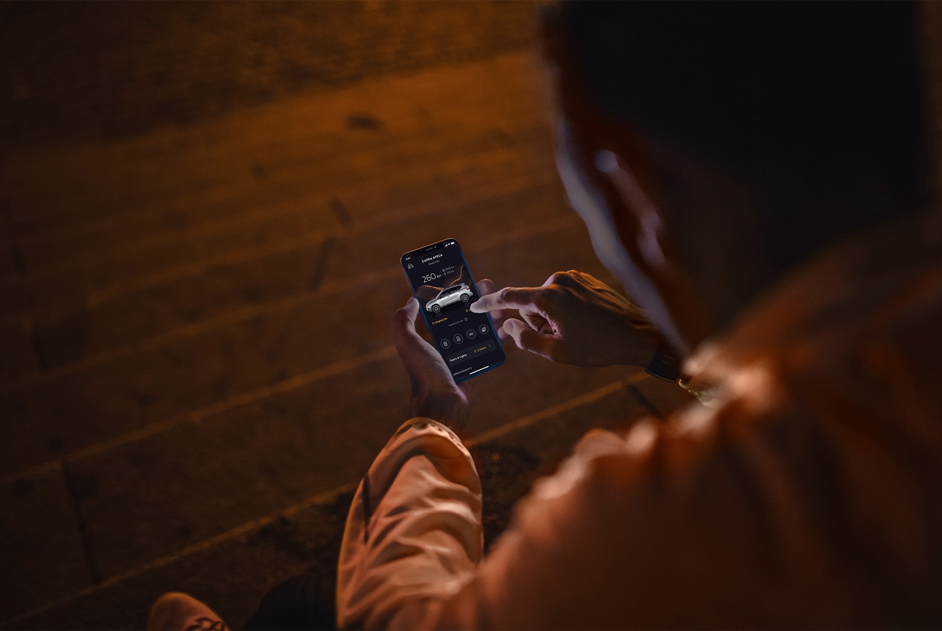 Los servicios online de CUPRA CONNECT incorporan una serie de soluciones para responder a los retos de la vida actual. Una persona sentada en unas escaleras por la noche, utilizando un smartphone con la pantalla iluminada.