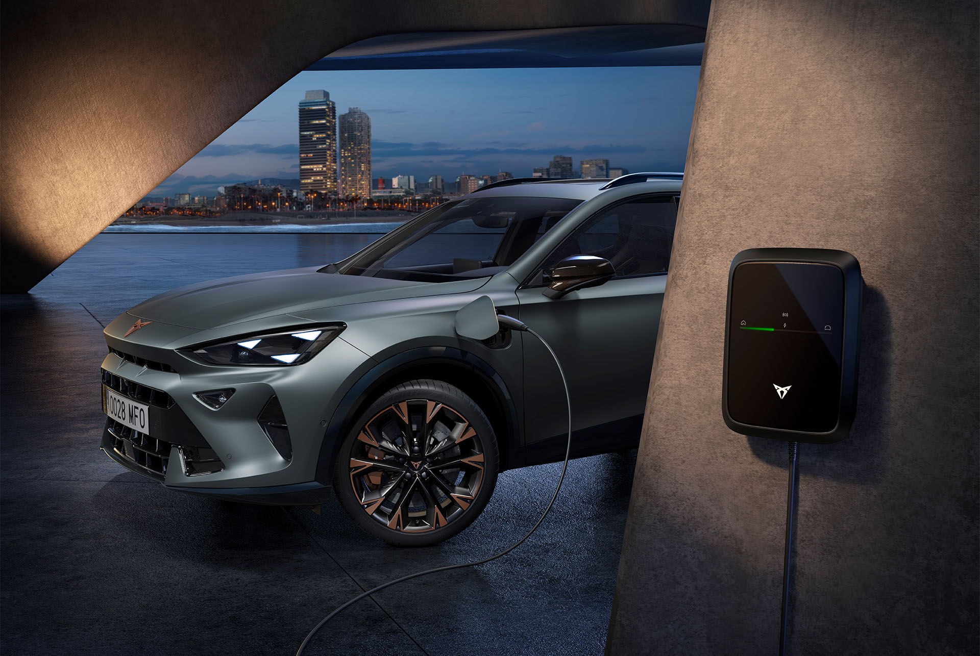 Vista lateral del CUPRA Formentor 2025 en color gris Enceladus Mate, aparcado en un lugar al aire libre, en la que se muestra el punto de carga del coche. 