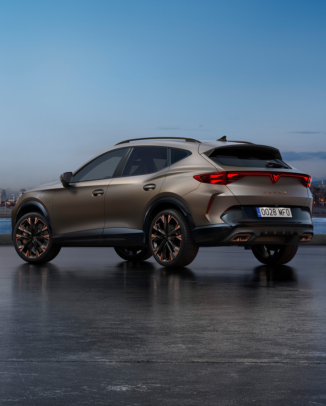 El nuevo SUV crossover CUPRA Formentor 2025 Century Bronze mate aparcado en un paseo marítimo durante el atardecer. El fondo muestra un paisaje urbano con rascacielos y palmeras iluminados por la luz del día, que se va atenuando.