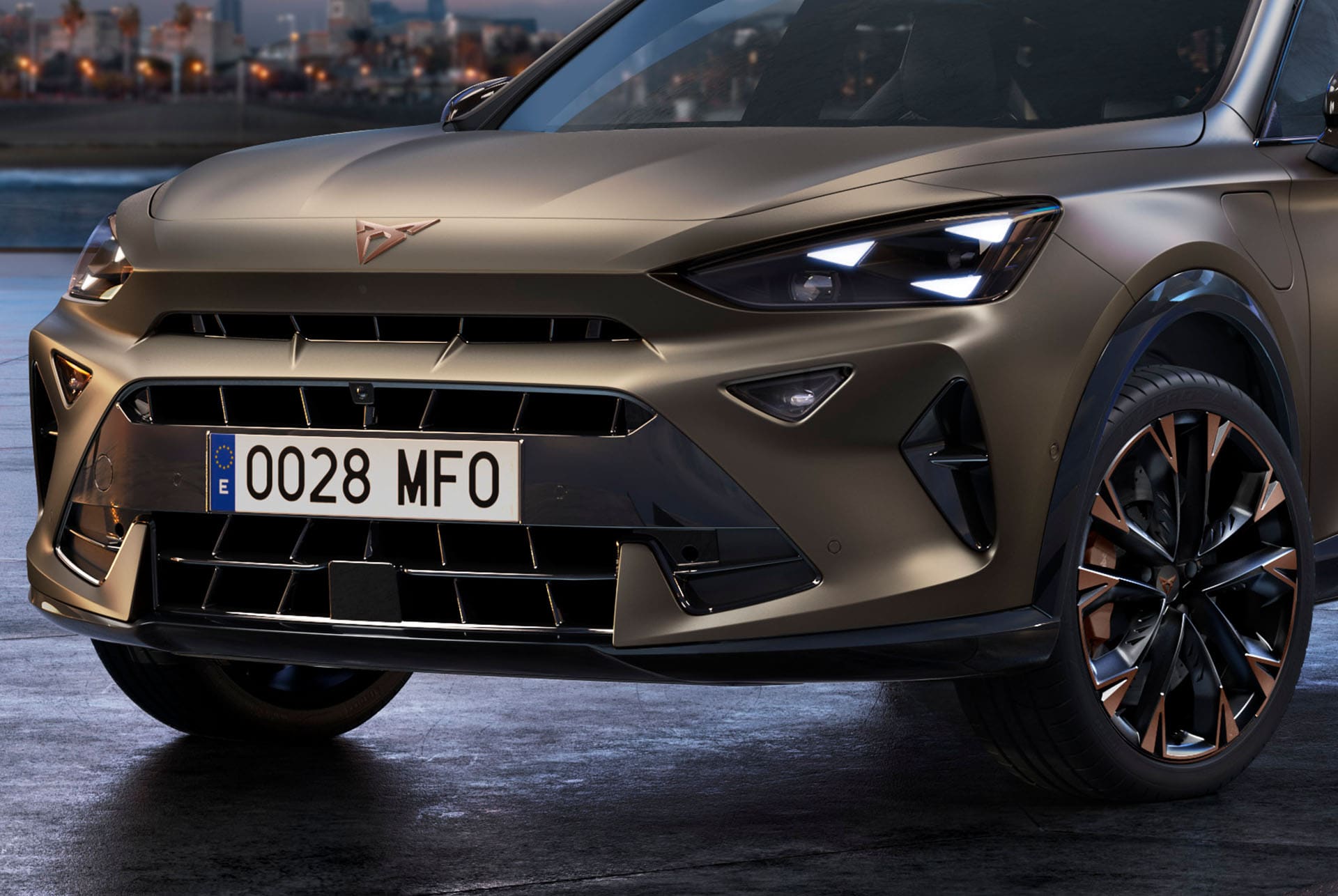Primer plano de la parte delantera de un CUV CUPRA Formentor 2025 de color Century Bronze, con llantas de acabado en Copper, los característicos faros delanteros con forma de ojo triangular y el distintivo logotipo CUPRA.