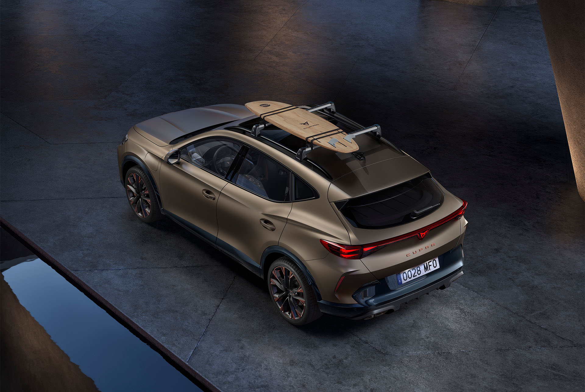 Vista de pájaro del nuevo CUPRA Formentor 2025 century bronze mate con accesorio portasurf en el techo, aparcado en hormigón.