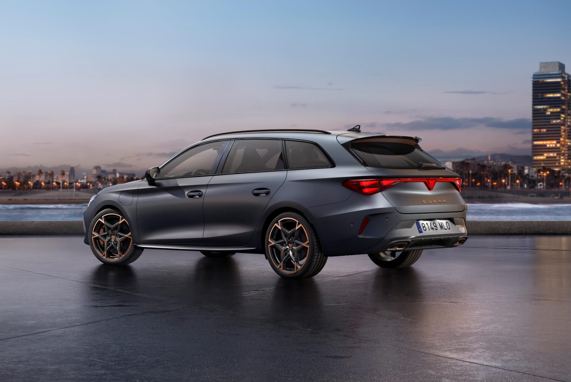 El nuevo y deportivo Cupra León Sportstourer 2025 aparcado sobre hormigón con el skyline de una ciudad iluminada al atardecer en el fondo. El vehículo aparece en un acabado gris mate.