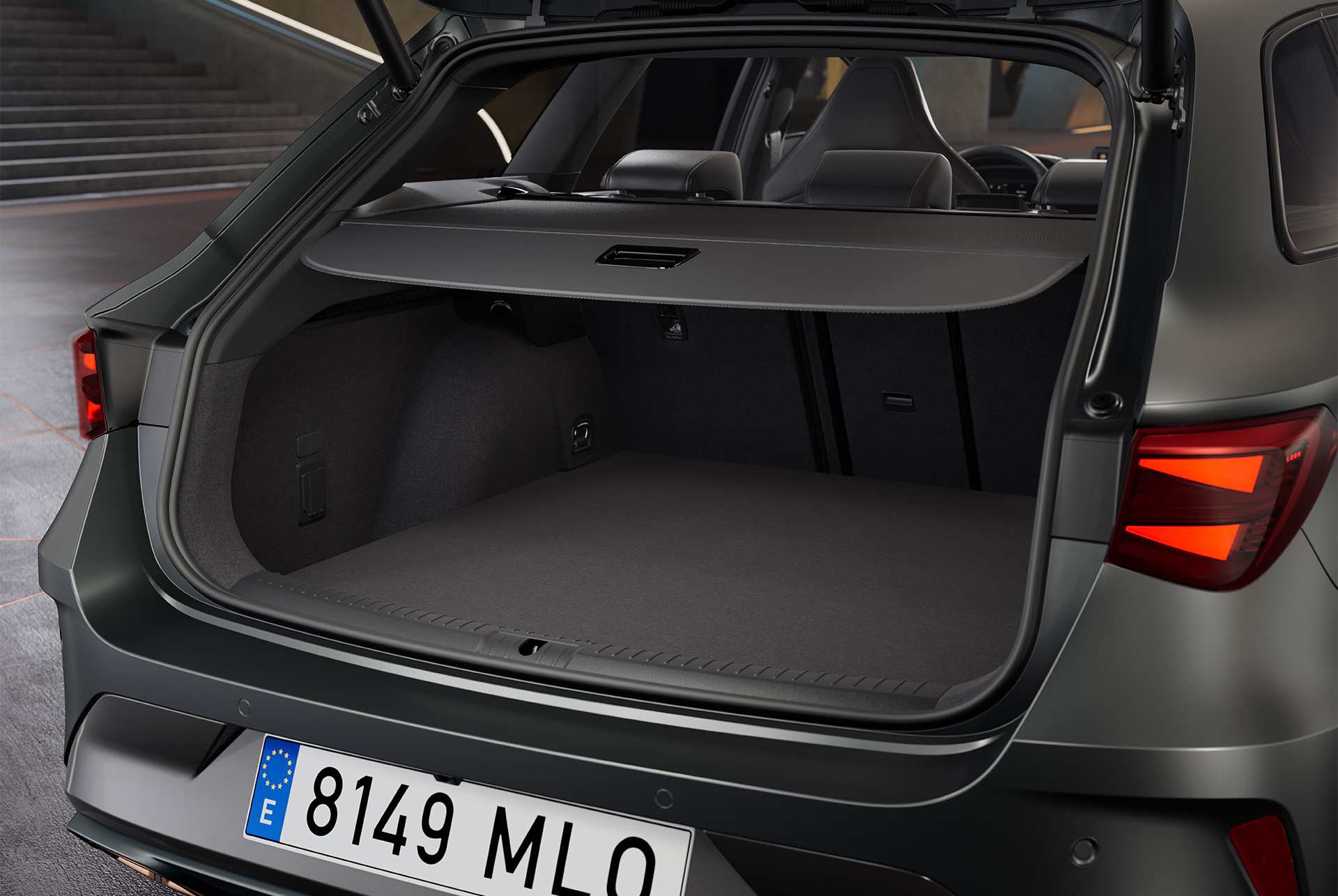 Maletero abierto del nuevo vehículo híbrido CUPRA León Sportstourer gris, que revela un gran espacio con interior negro. Dentro del maletero hay una bolsa.