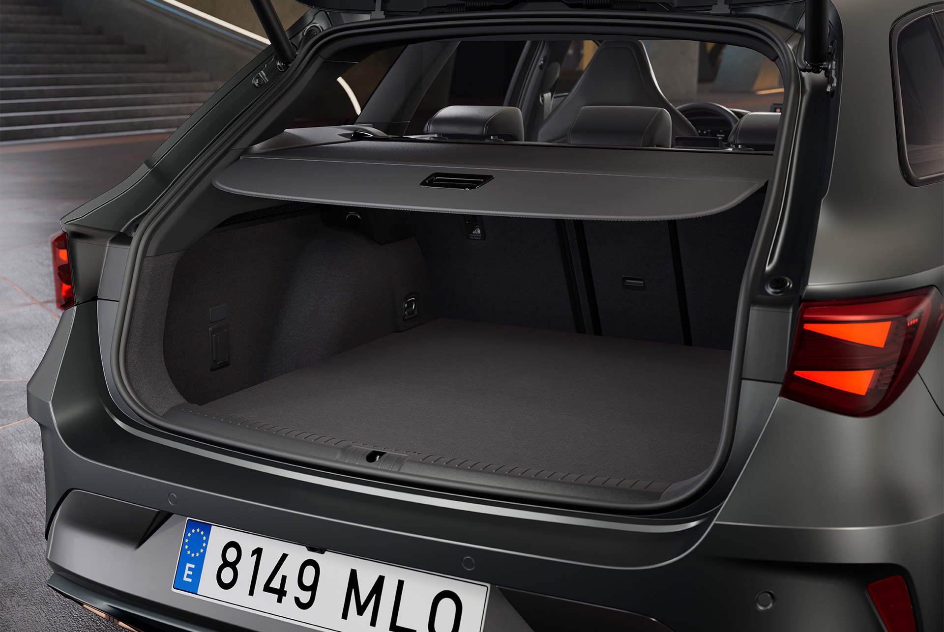 Maletero abierto del nuevo vehículo híbrido CUPRA León Sportstourer gris, que revela un espacioso maletero con interior negro. Dentro del maletero hay una bolsa.