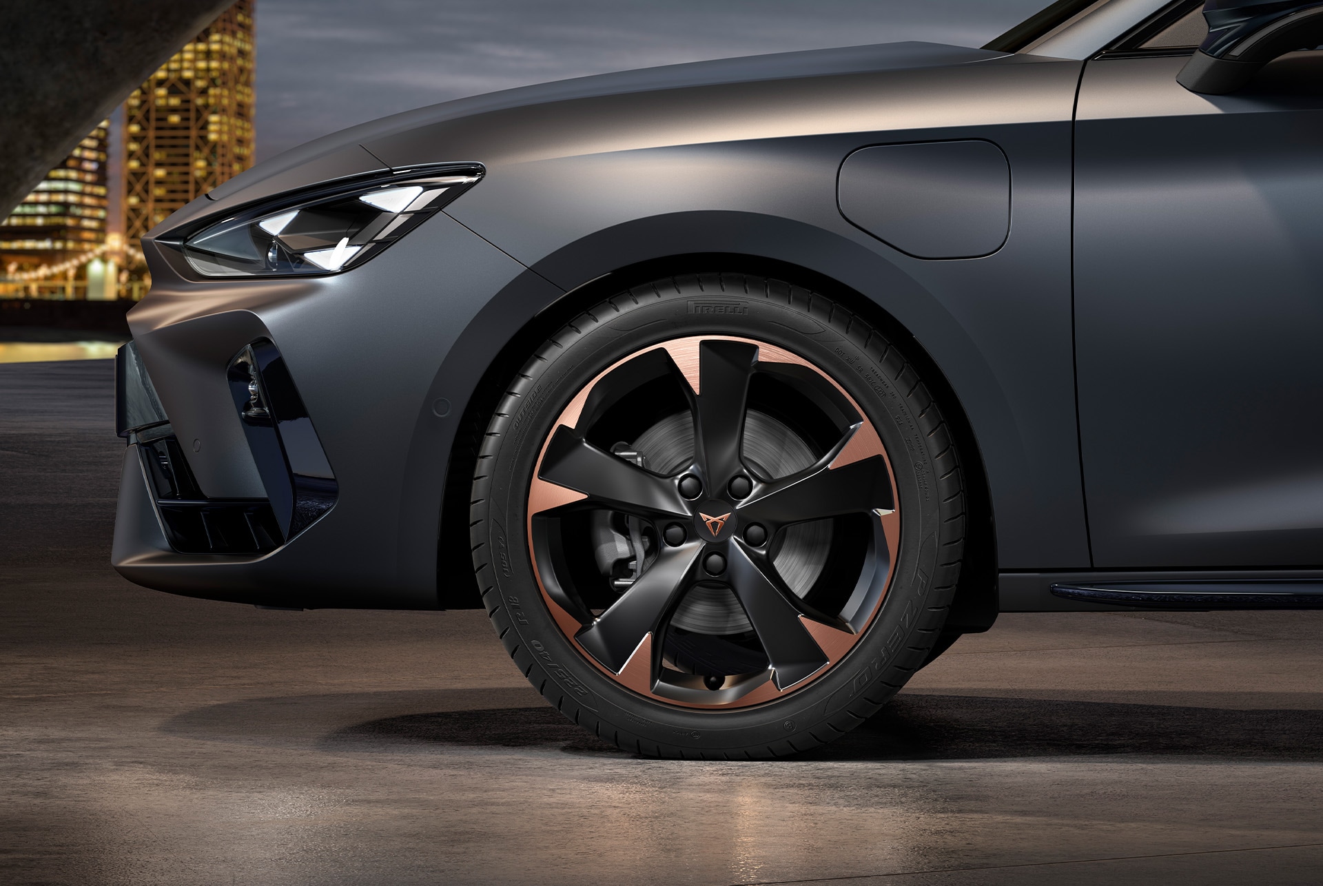 vista frontal lateral izquierda de las llantas de aleación mecanizadas Mistral Garbi Copper para el nuevo CUPRA León Sportstourer 2025, neumáticos, faros característicos y carrocería gris