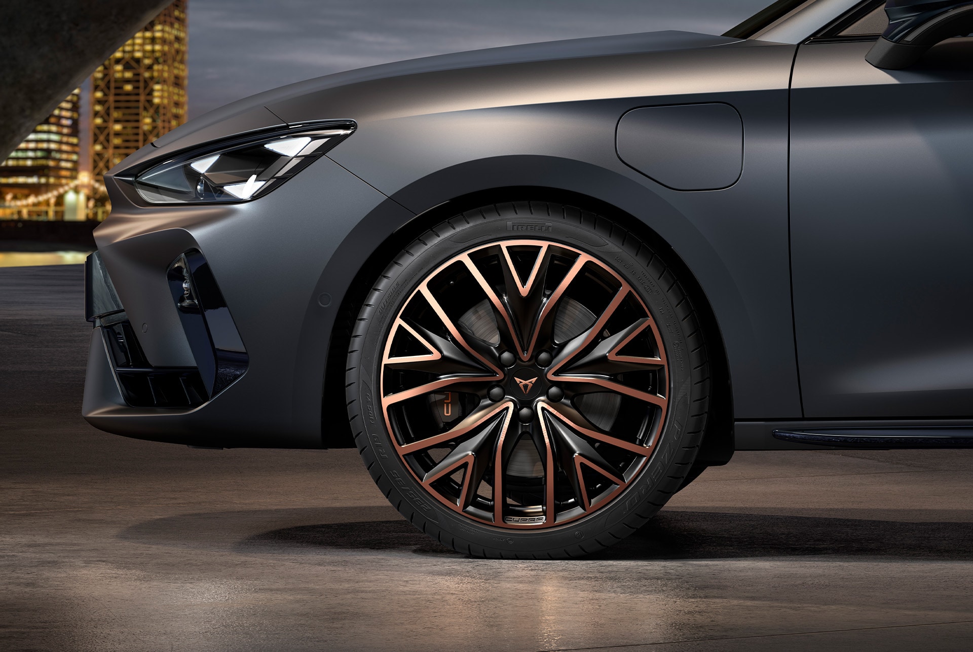 vista lateral delantera de las llantas forjadas Mistral Copper izquierdas en cobre y negro para el nuevo CUPRA León Sportstourer 2025, neumáticos, faros característicos y carrocería gris
