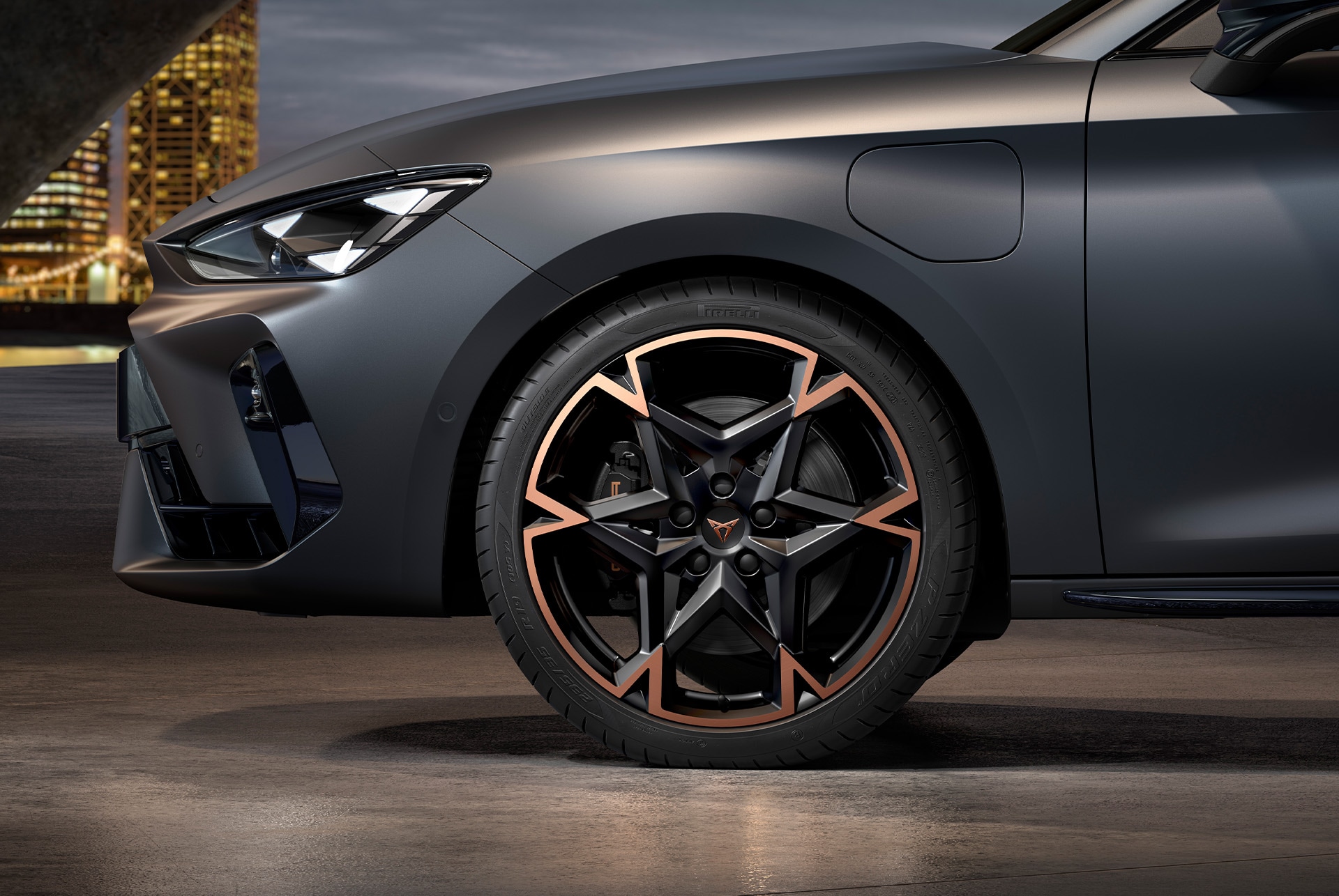 vista lateral delantera de la llanta de aleación mecanizada izquierda en negro y cobre para el nuevo CUPRA León Sportstourer 2025, neumáticos, faros característicos y carrocería gris