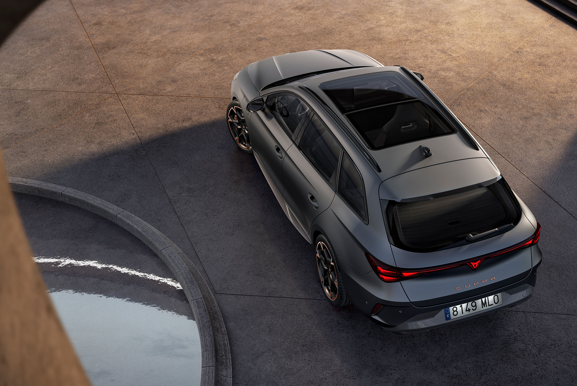 Tecnología de coche híbrido del nuevo CUPRA León Sportstourer 2025, aparcado sobre cemento, vista de águila con techo solar panorámico y portón trasero eléctrico