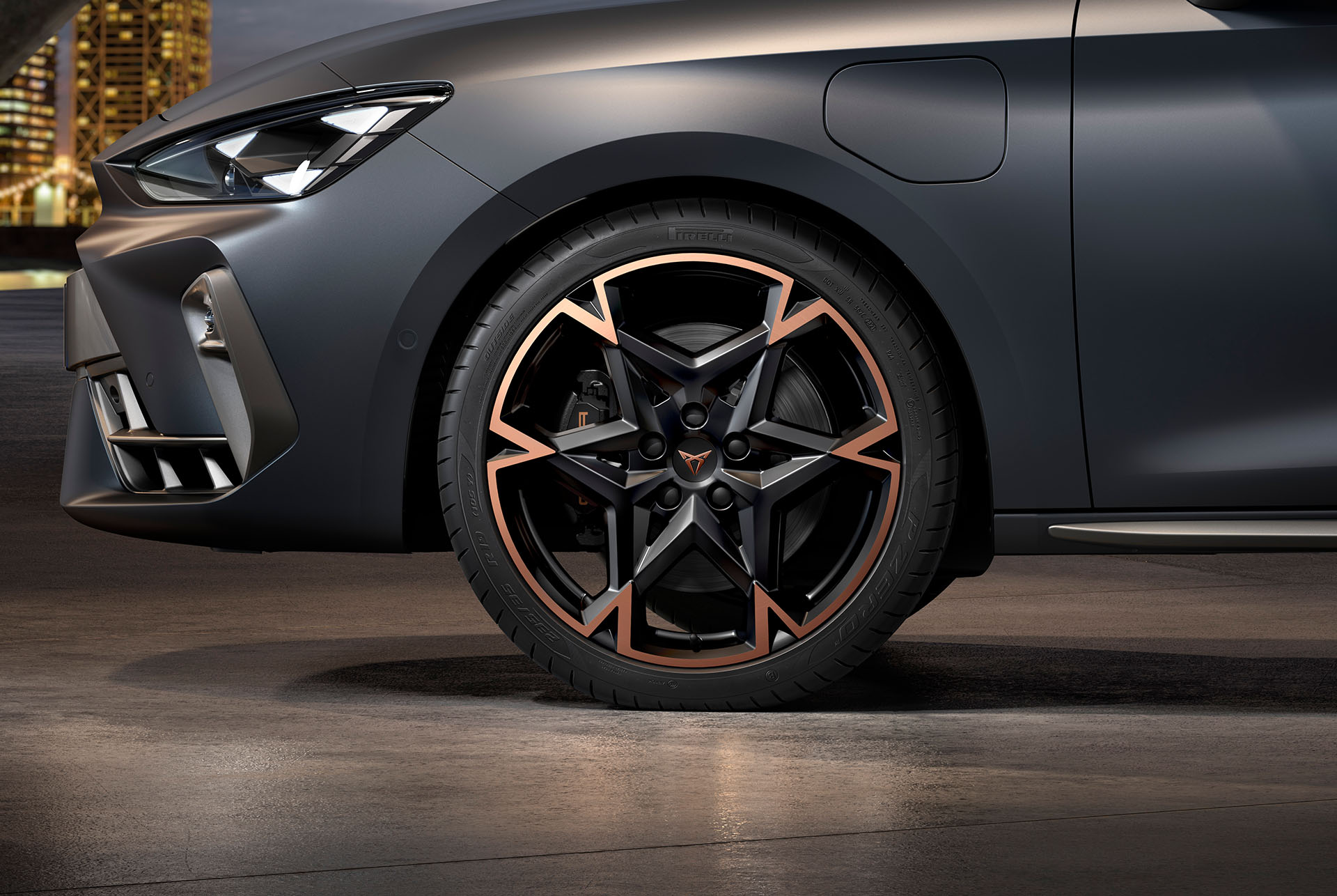 vista lateral delantera de la llanta de aleación mecanizada izquierda en negro y cobre para el nuevo CUPRA León 2025, neumáticos, faros característicos y carrocería gris mate