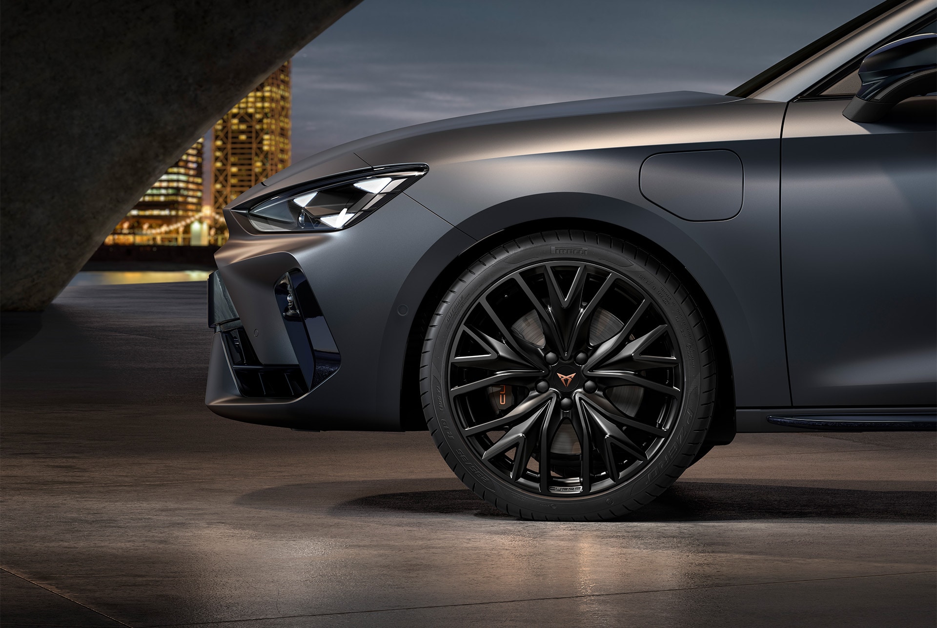 front side view of left alloy wheel in sport matt black for the Cupra Leon, tyres, signature headlights and matt grey body.