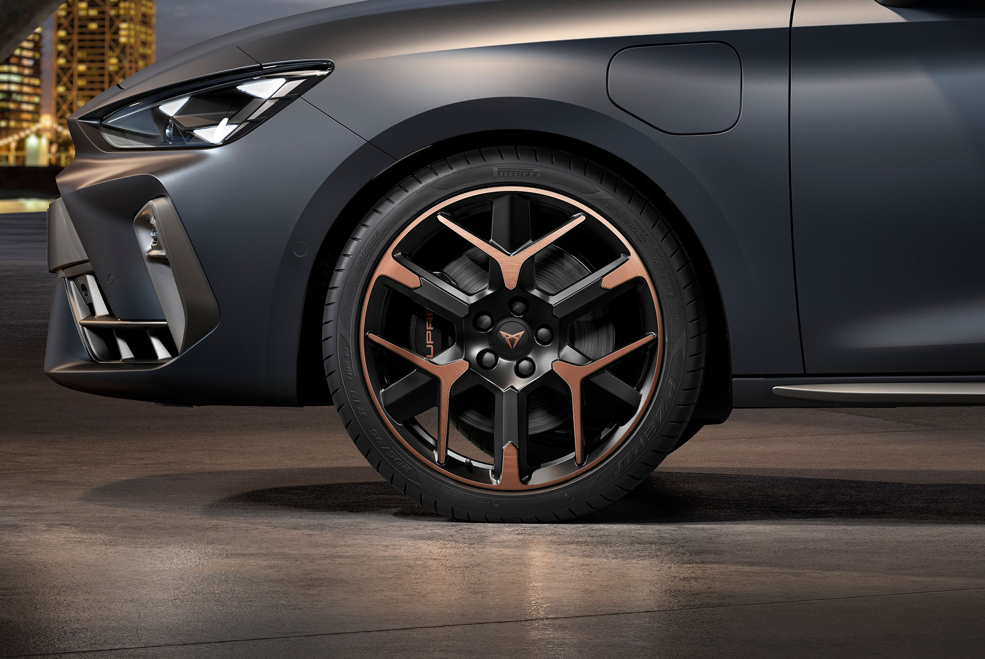 vista lateral delantera de la llanta de aleación forjada izquierda en cobre y negro para el nuevo CUPRA León 2025, neumáticos, faros característicos y carrocería gris mate