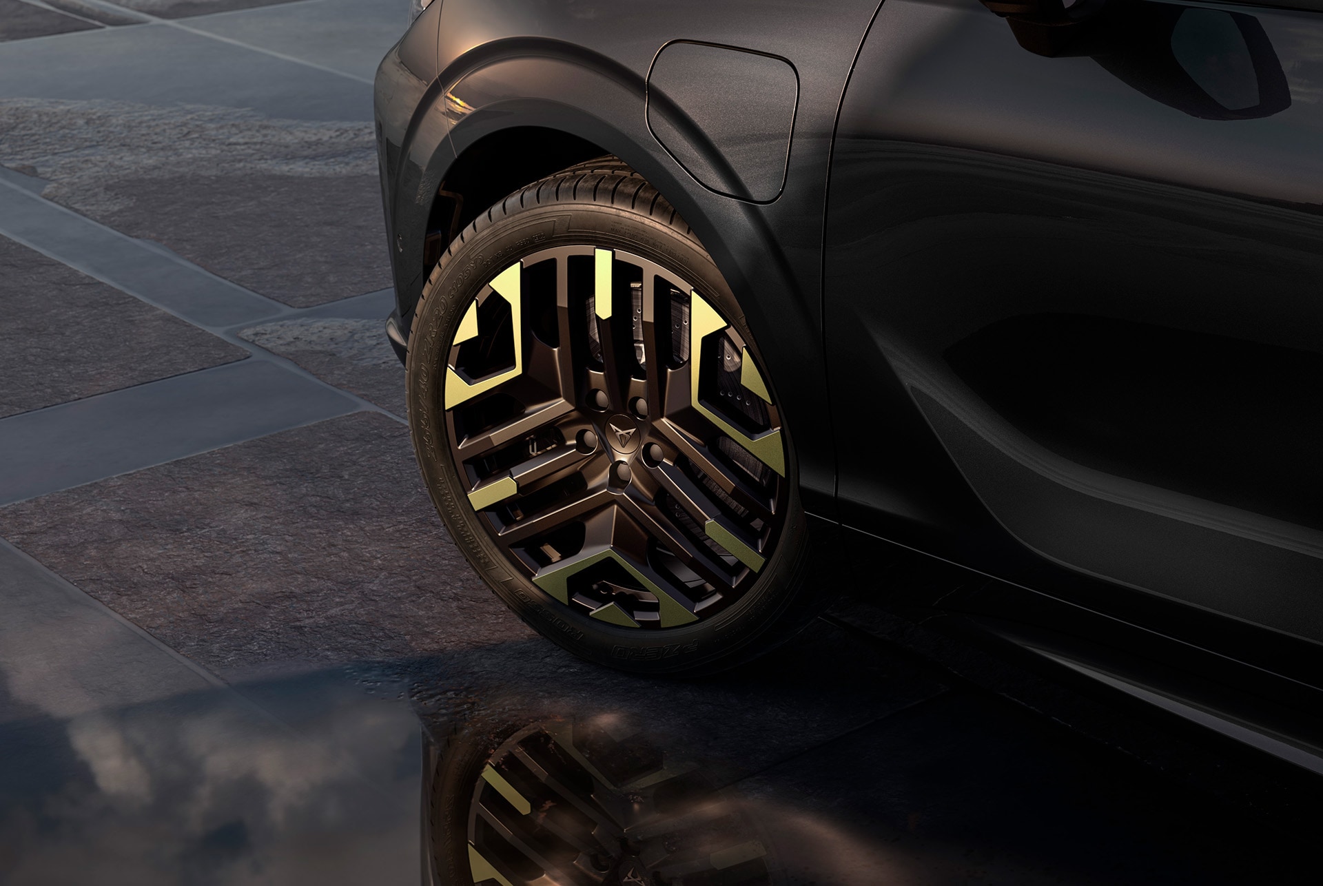Llanta de aleación izquierda de 50,8 centímetros (20") de color Sulfur en el CUPRA Terramar de la nueva Tribe Edition, sobre un pavimento de azulejos oscuros que complementa la carrocería oscura brillante
