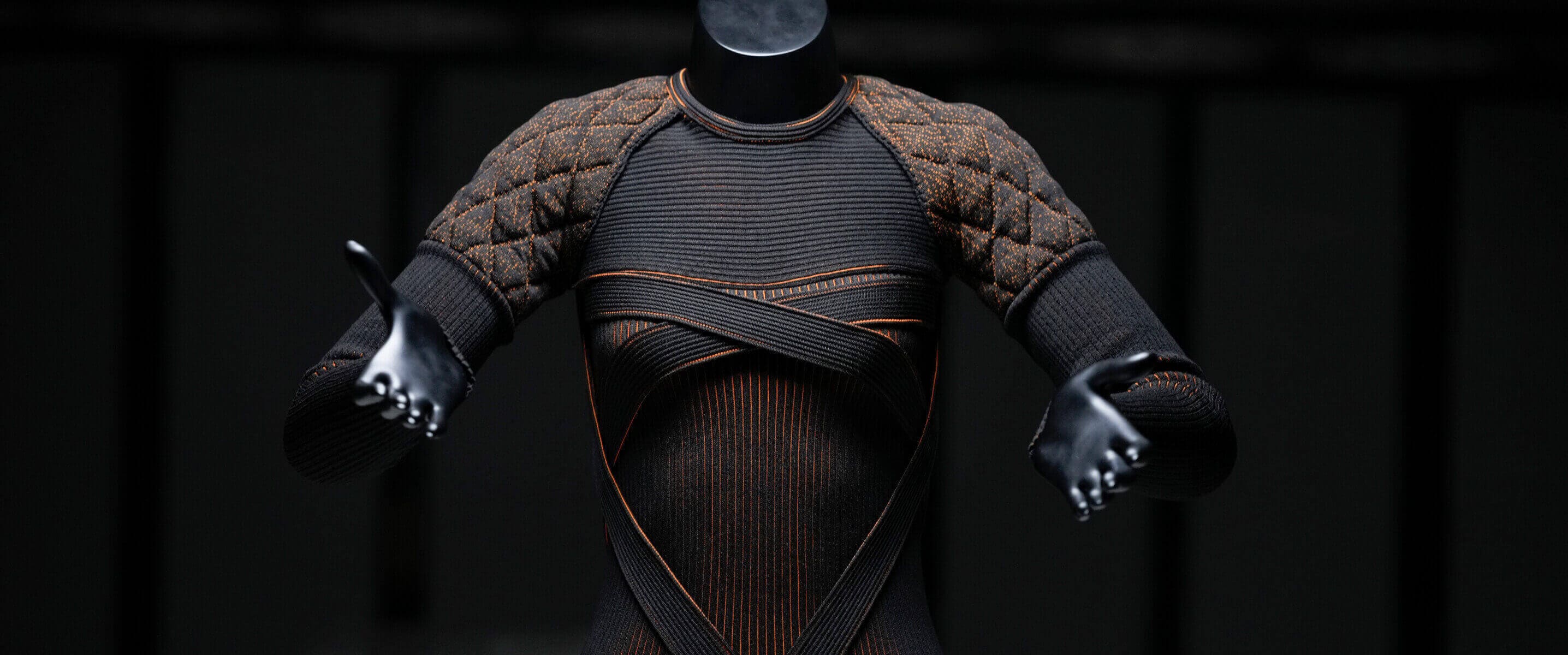 Top con textura expuesto en un maniquí negro sobre fondo oscuro, apoyado en una superficie blanca.
