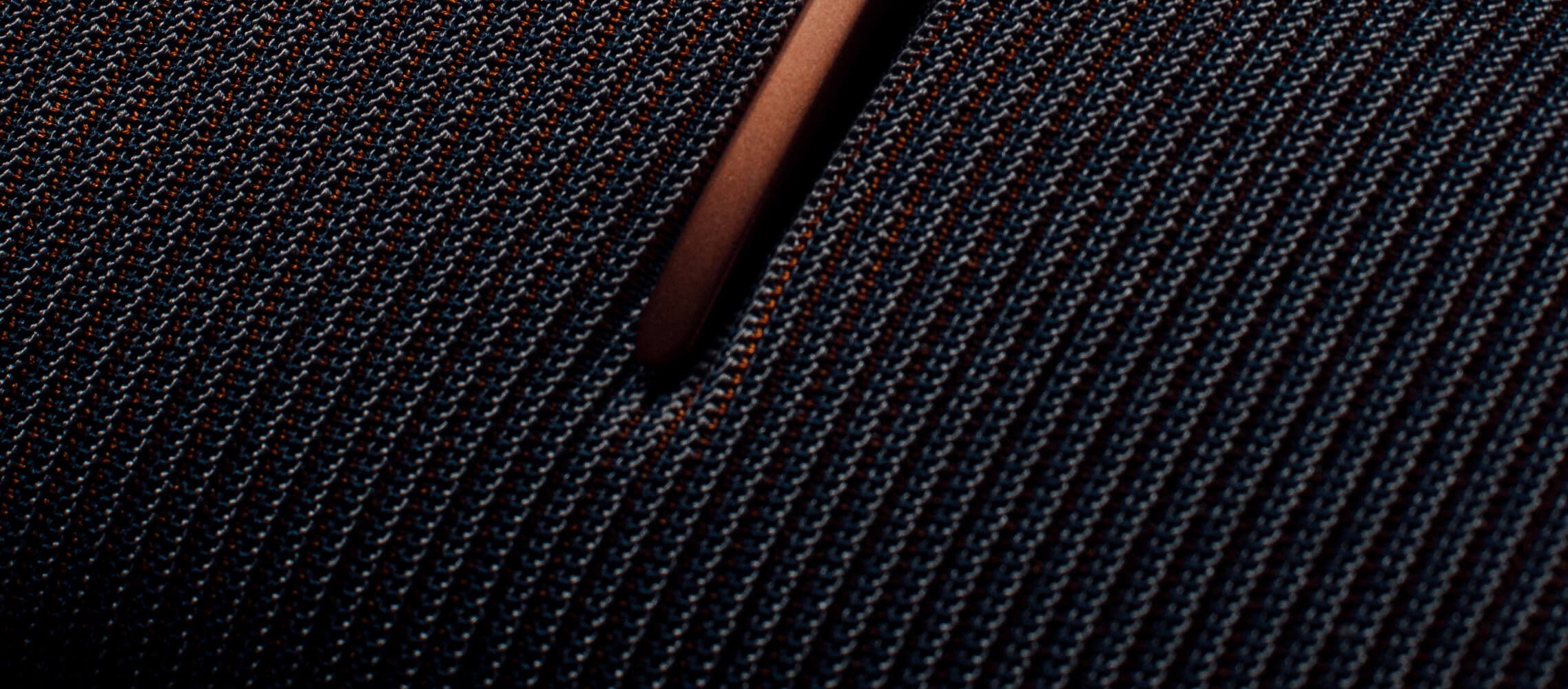 Primer plano de un tejido texturizado y tupido con un estampado azul oscuro y naranja.