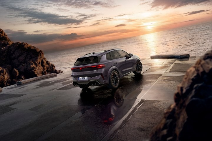 Rear view of a new cupra terramar parked in front of the sea, looking at the sunset.
