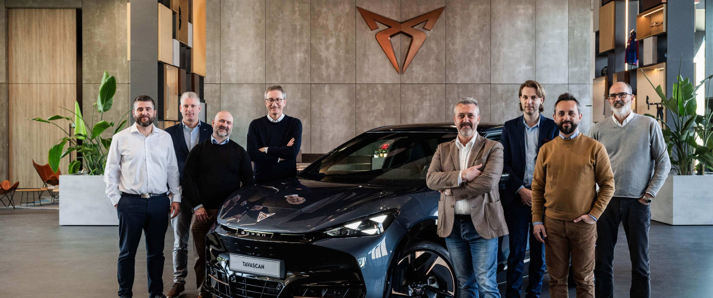 Vehículo CUPRA Tavascan dentro de un showroom con administradores de flotas, logotipo CUPRA de cobre en la pared.