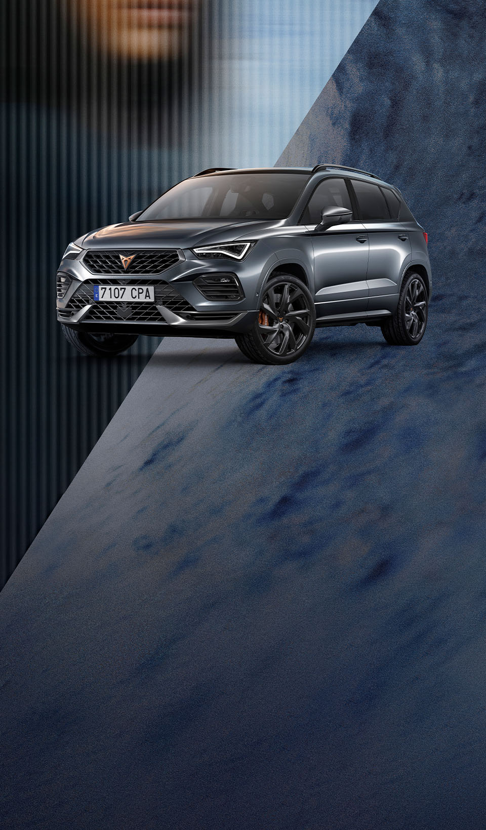 Un CUPRA Ateca SUV aparcado con los faros encendidos girado ligeramente hacia el espectador, muestra su parrilla frontal distintiva, faros y llantas con acentos en cobre “Copper” con fondo desenfocado en un patrón abstracto que deja intuir una cara de persona