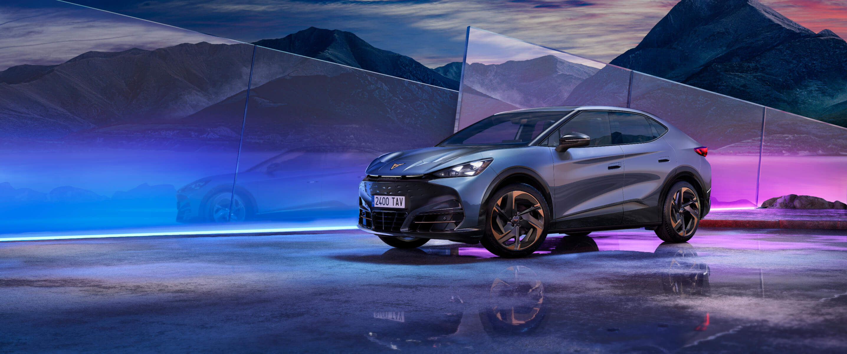 Un CUPRA Tavascan gris, en un ángulo de visión frontal, rodeado de luces tenues multicolores.