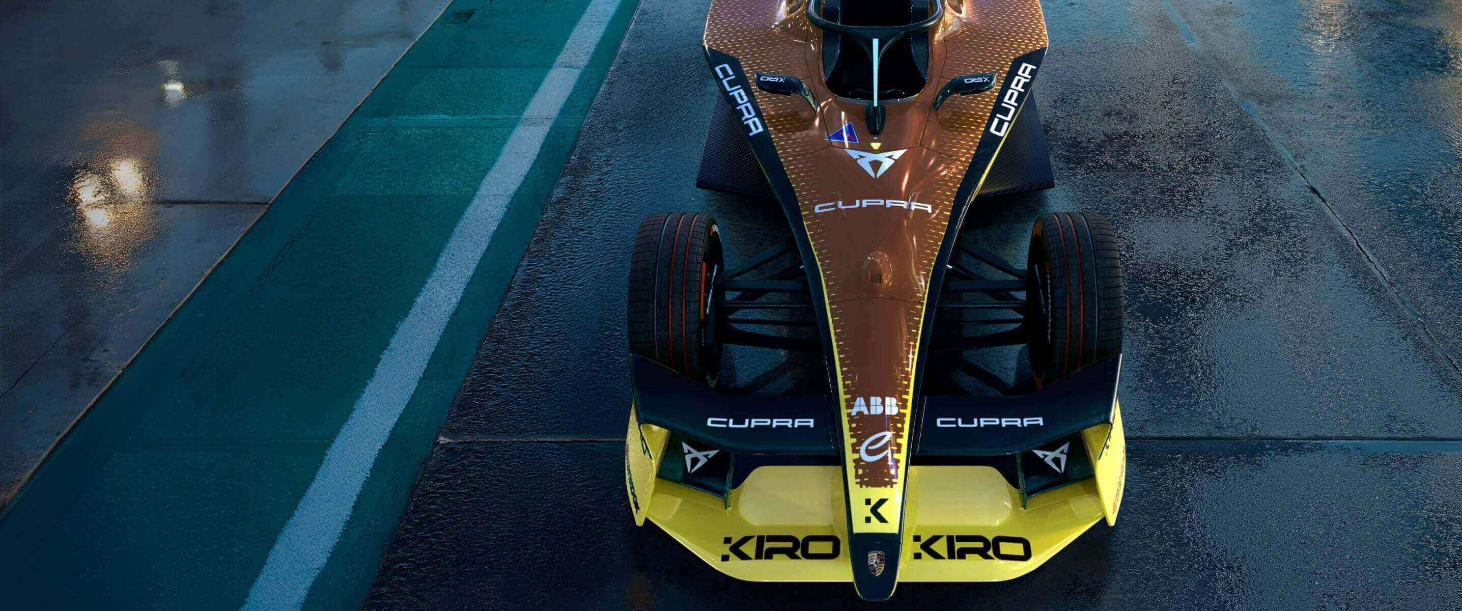 Vista frontal del CUPRA Kiro de Fórmula E, luciendo su librea inspirada en el diseño copper con audaces detalles en negro y amarillo, diseñado para la temporada 2025 de Fórmula E, sobre una pista de carreras mojada. 